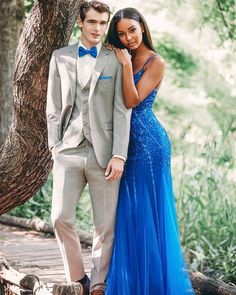 a man in a tuxedo and a woman in a blue dress standing next to each other