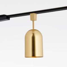 a gold colored light fixture hanging from a black metal bar over a white wall and floor