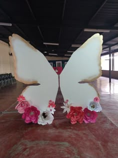 two large white butterflies with pink and red flowers on them sitting in an empty room