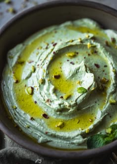 a bowl filled with green hummus on top of a table