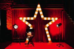 a red stage with two lights and a star on the wall next to a chair