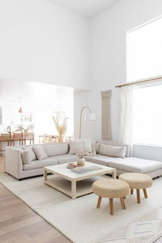 a living room filled with furniture and a large white rug on top of a hard wood floor