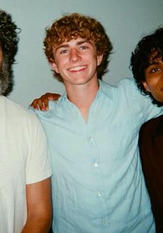 three men standing next to each other smiling