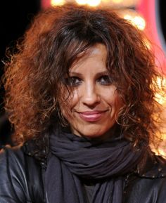 a close up of a person wearing a leather jacket and scarf with lights in the background