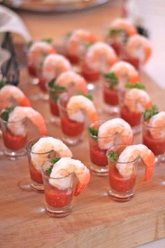 small cups filled with shrimp and garnish on top of a wooden table