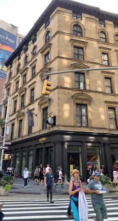 people are crossing the street in front of a large building with many windows on it