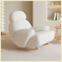 a white rocking chair in a living room with books on the shelves and a lamp next to it