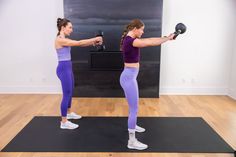 two women doing exercises with kettles in a gym