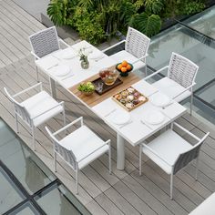 an outdoor table with white chairs and plates on it