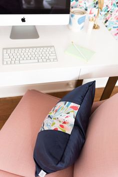 a pillow sitting on top of a pink chair in front of a computer monitor and keyboard