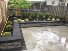 an outdoor patio area with stone walls and plants in the center, surrounded by wooden fence