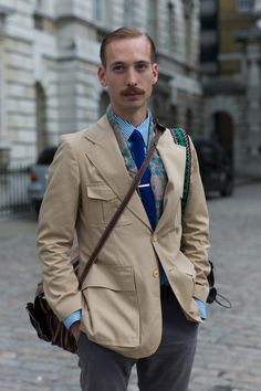 Vintage safari street style at #LFW combines menswear classics with perfectly hand-picked accessories. The lightweight 4-pocket jacket is a great example of functional, military-inspired tailoring, while the print scarf and woven camera strap offset that dapper Bengal stripe shirt and tie with a well-travelled edge.  WGSN street shot, London Fashion Week Vintage Safari, Safari Jacket, Vintage Fits, Men Street, Pocket Jacket, Military Inspired, Field Jacket, Street Style Outfit, Scarf Print