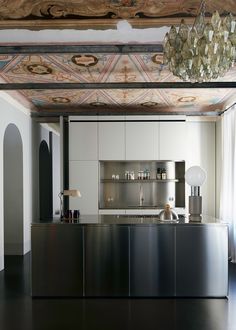 a kitchen with an island and chandelier hanging from it's ceiling above the counter