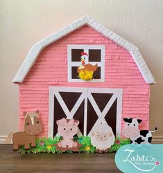 a pink barn with three farm animals and a chicken on the roof, sitting in front of it