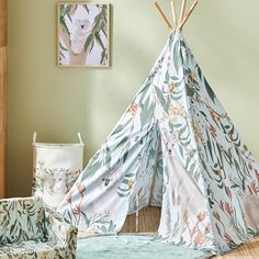 a teepee is sitting on the floor in front of a wall with pictures hanging above it