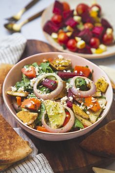 a bowl filled with salad next to bread