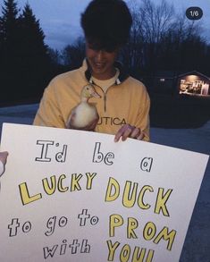 a man holding up a sign with a duck on it's chest and the words i'd be a lucky duck to go to prom with you