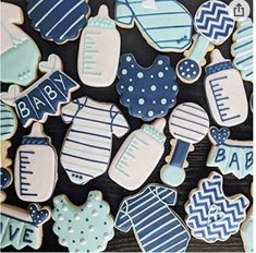 baby shower cookies are arranged on a black table with blue and white decorations, including ones that say it's a boy