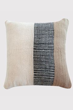 a black and white striped pillow with two different colors on the front, one is beige