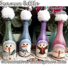 four colorful vases with snowmen and flowers in them on a doily next to a potted plant