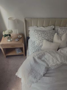 a bed with white linens and pillows in a bedroom next to a night stand