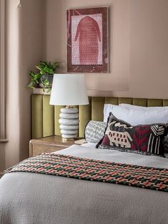 a bedroom with pink walls, white bedding and two lamps on either side of the bed