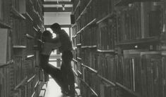 two people standing in the middle of a library filled with books