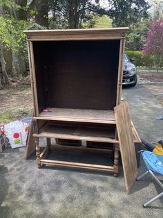 an open wooden box sitting on the ground next to a child's high chair