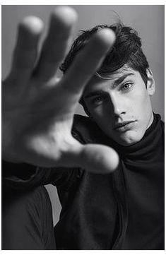 black and white photograph of a young man holding his hand up to the camera with both hands