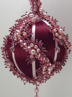 a red ornament with pearls and ribbon