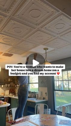 a woman standing in a kitchen next to a dining room table with chairs on it