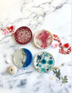 three bowls with different colors and designs on them sitting on a marble counter top next to seashells