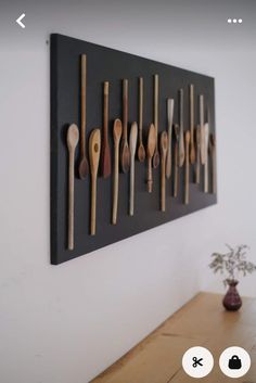 wooden spoons hanging on the wall in front of a vase