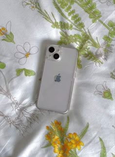 an iphone case sitting on top of a bed covered in yellow and green floral fabric