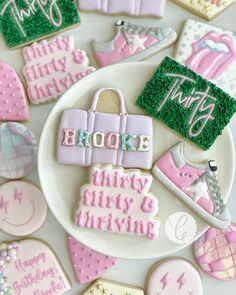 decorated cookies are arranged on a plate with the words broke, happy birthday and pink shoes