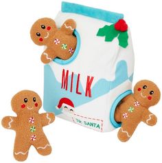 three stuffed gingerbreads are in front of a milk can with santa claus on it