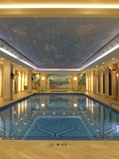 a large indoor swimming pool in a hotel with skylights and stars on the ceiling