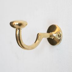 a close up of a gold hook on a white wall