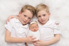 two young children cuddle together while holding their newborn baby's head in the arms