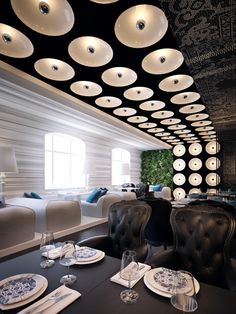 a dining room with black and white decor on the ceiling, leather chairs and plates