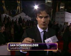 a man in a suit and tie is talking to someone on the red carpet at an event