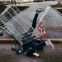 a person laying on the ground with a shopping cart in front of them that is upside down