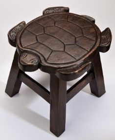 a small wooden stool with carved designs on the top and bottom, sitting against a white background