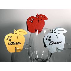 three wine glasses with cut out paper apples on the top and bottom, sitting next to each other