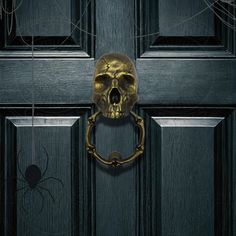 a golden skull hanging on a door handle with a spider crawling by it's side