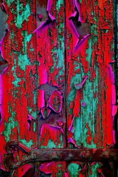 an old wooden door with peeling paint on the outside and red paint on the inside