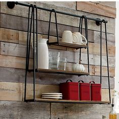 two metal shelves holding dishes and cups on top of a wooden wall next to a sink