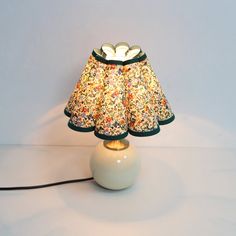 a lamp that is sitting on top of a white table with a flowered lampshade