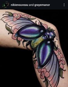 a woman's arm with tattoos on it and flowers around the wrist, in front of her is an image of a purple flower