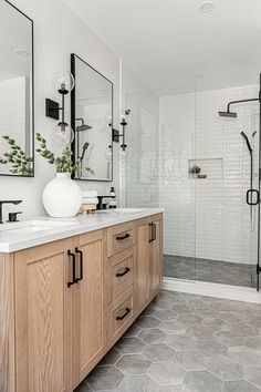 a bathroom with two sinks, mirrors and a shower stall in the middle of it